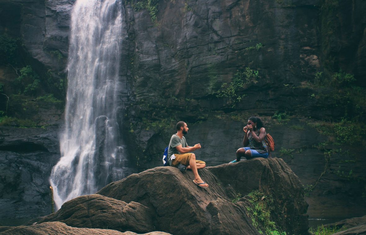 Friends sit by a waterfall in Pariyaram, India.